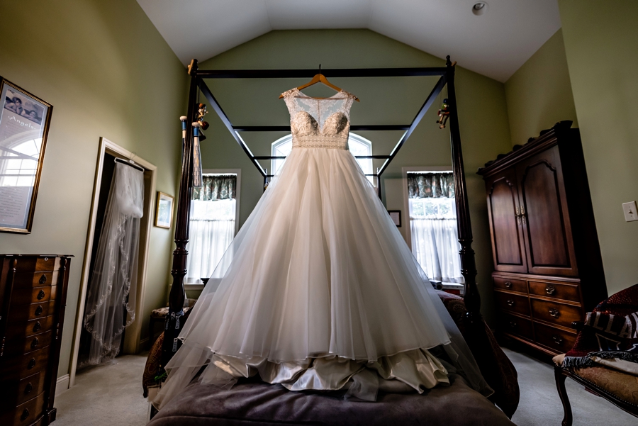 A bride's wedding dress hanging on the bed in her childhood home in philadelphia.